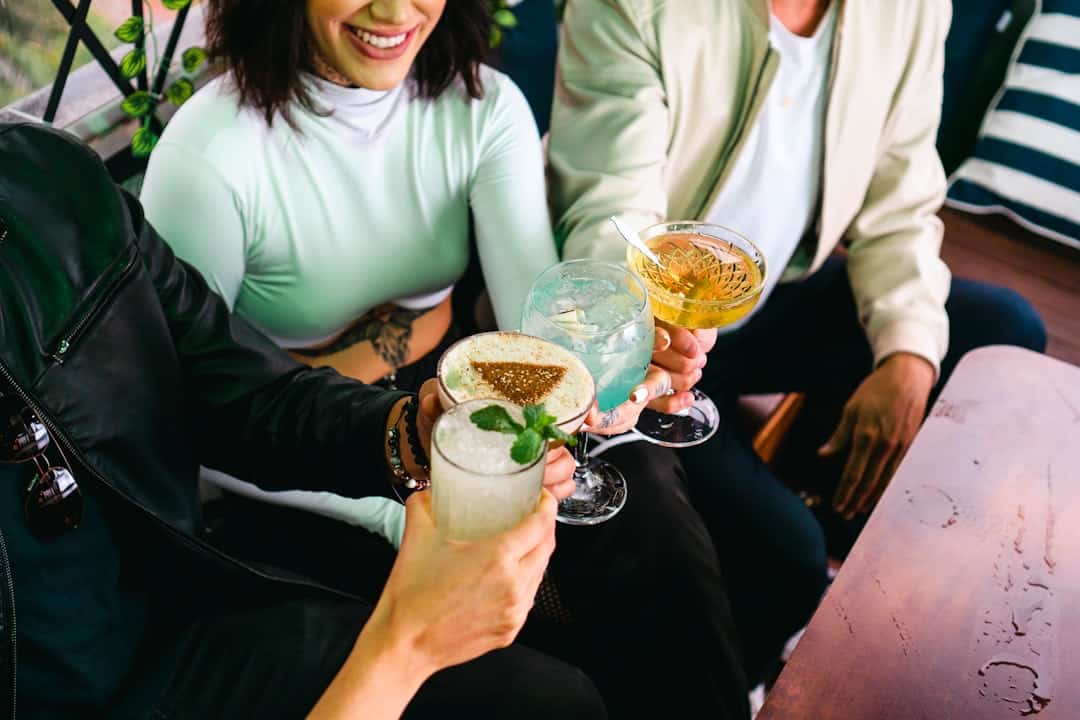 group of friends laughing holding cocktails on a sunny cruise deck